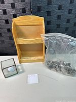 Group shot of pine wall shelf, glass cube, and bag of metal pinecones