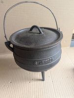 Full view of cast iron cauldron showing three legs, lid, and handle