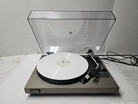 Front view of Technics SL-23 turntable with dust cover open and record on platter