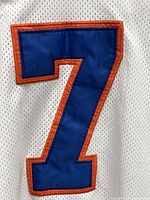 Close-up of blue #7 with orange outline on white mesh fabric