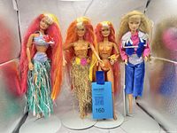 Group shot of all four Barbie dolls standing on display stands