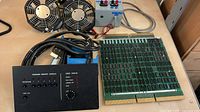 All items laid out on desk: memory board, tester panel, power box, two fans, cables
