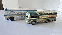 Two Greyhound tinplate buses side by side, fronts and sides visible