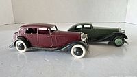 Side view of burgundy sedan and green coupe showing body colors, fenders and tires