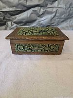 Angle view of closed wooden box showing lid mosaic and side panel