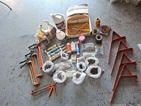 Full lot overview showing fasteners, caulking guns, adhesive containers, brackets, strapping