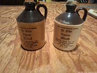 Front view of both Cornish Mead stoneware jugs showing printed labels and coloration