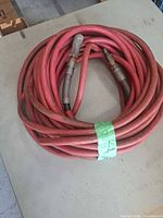 Coiled red rubber air hose on table