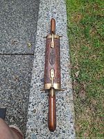 Closed sheath showing carved design and brass fittings