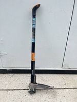 Full view of Fiskars stand-up weeder leaning against wall