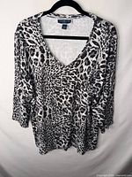 Front view of Karen Scott black and white leopard print 3/4 sleeve V-neck top on hanger