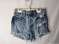 Front view of distressed light blue denim shorts showing rips and frayed hems