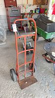 Front view of red steel hand truck with two wheels and toe plate