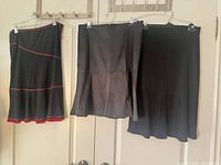 Three skirts hanging: polka-dot with red trim, pinstripe, solid black