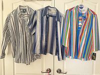 Three blouses hanging on doors showing front views
