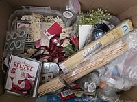 Top view of box showing wood cutouts, ribbon, skewers, tins, adhesive dots, booklet, greenery