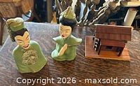 Group shot showing both bust figurines and wooden cabin