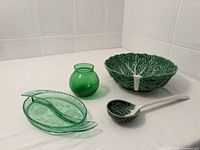 Group shot of cabbage leaf bowl, ladle, two green glass dishes and bud vase
