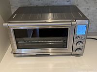 Front view of Breville stainless steel toaster oven showing glass door, handle, and control panel