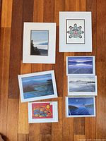 All seven matted prints laid out on wood floor