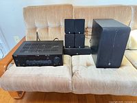 Front view of receiver, five small speakers and subwoofer arranged on sofa