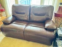 Front view of dark brown faux leather loveseat showing split back cushions and pillow armrests