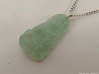 Front view of carved jadeite pendant on silver chain