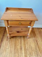 Front view of wood side table showing drawer, shelf and turned legs