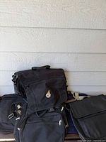 Group of four black messenger/laptop bags stacked together