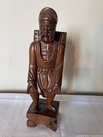 Front view of carved wood figurine showing facial details, robe, and stand