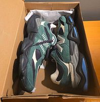 Side view of both sneakers inside box showing colorway and materials