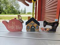 All three wooden decorative pieces side by side with tape measure for scale