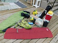 Full view of both sleeping bags, folding chair, cooler, backpack, soccer ball, baseball mitt, and camping accessories on deck