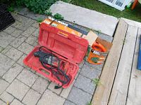 Black & Decker hedge trimmer box and Milwaukee Sawzall in carrying case on pavement.