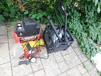 Full lot overview showing a Husky air compressor tank, yellow coiled hose, red grease gun with pressure gauge, and black crate with steam cleaner attachments.