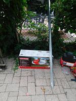 Unopened Craftsman opener box and metal rail section leaning against fence