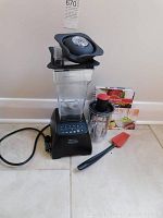 Overview of blender base with large jar and lid, Twister jar, spatula, and two recipe books