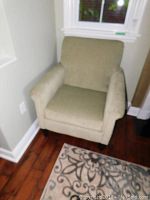 Full view of green fabric easy chair against wall, showing overall shape and size.