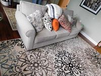 Full front view of light gray fabric couch with four throw pillows on living room rug