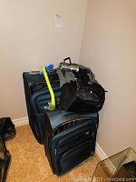 Photo showing three bags including two large blue suitcases stacked with a black toiletry bag on top along with a yellow snorkel and flashlight