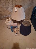 Group shot showing ceramic lamp base, two boxed clip-on lamps, beige and navy shades