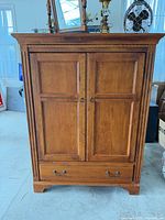 Front view of Ethan Allen wooden cabinet with doors closed and bottom drawer visible