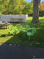 Four green patio chairs grouped on lawn