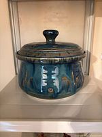 Vessel front view showing lid, glaze, carved motifs