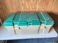 Closed Rubbermaid tote showing green lid, beige base and latches