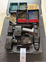 Drill, batteries, charger, bit sets arranged in open carry case