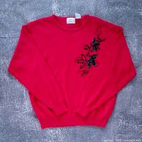 Full view of red sweater front displaying beaded floral design