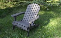 Foldable gray-green wooden Adirondack chair upright on lawn
