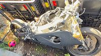 Left side view of damaged Suzuki GSX-R showing frame, swingarm, rear wheel, gold forks, front wheel