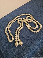 Full view of long faux pearl necklace laid out showing continuous loop
